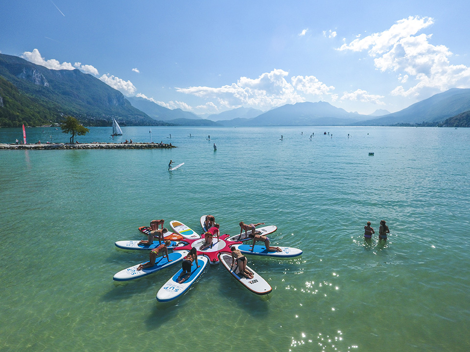 photo du lac d'annecy avec en premier plan une session de yoga paddle